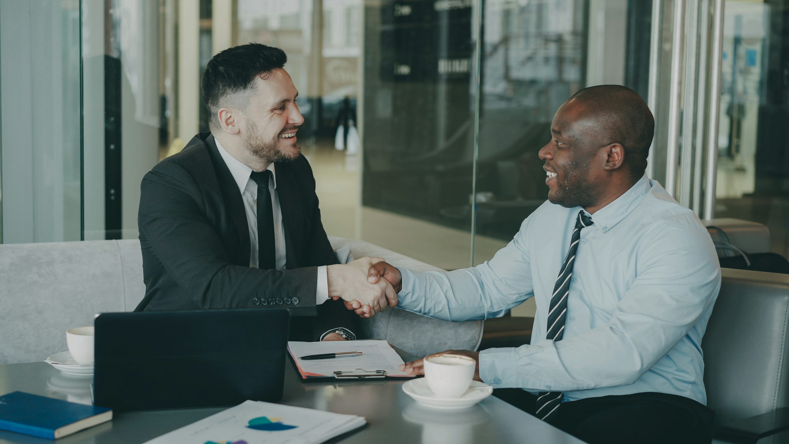 Business executives shaking hands across a boardroom table